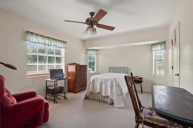 carpeted bedroom featuring a textured ceiling, multiple windows, and ceiling fan