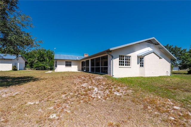 back of house featuring a sunroom and a lawn