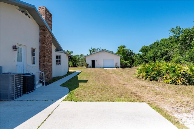 view of yard with a garage, an outdoor structure, and central AC