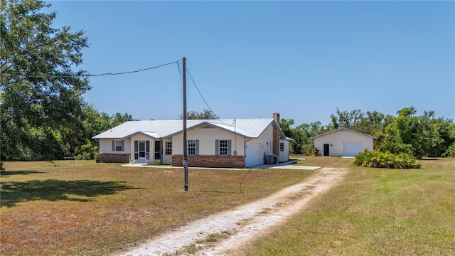 ranch-style home featuring a front yard, an outbuilding, and a garage