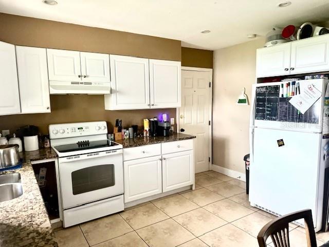 kitchen with white appliances, white cabinetry, and under cabinet range hood