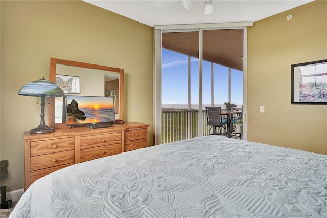 bedroom with expansive windows, access to exterior, and multiple windows