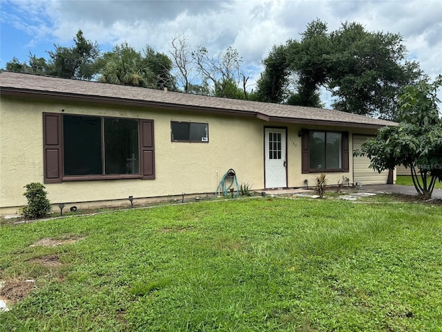 view of front of home with a shingled roof, a front lawn, and stucco siding