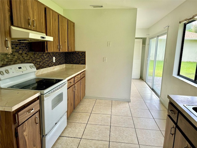 kitchen with white electric stove, light tile patterned floors, tasteful backsplash, visible vents, and under cabinet range hood