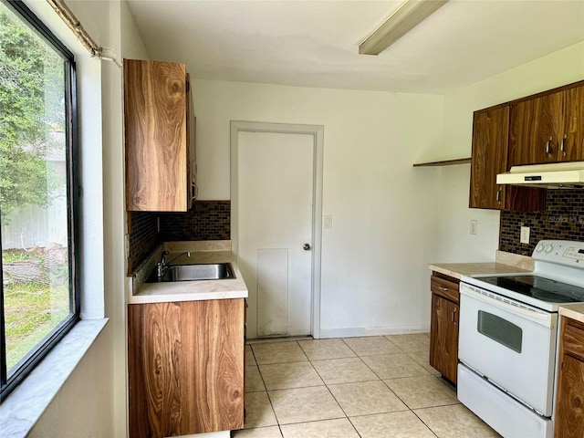 kitchen featuring light tile patterned flooring, under cabinet range hood, electric range, a sink, and light countertops