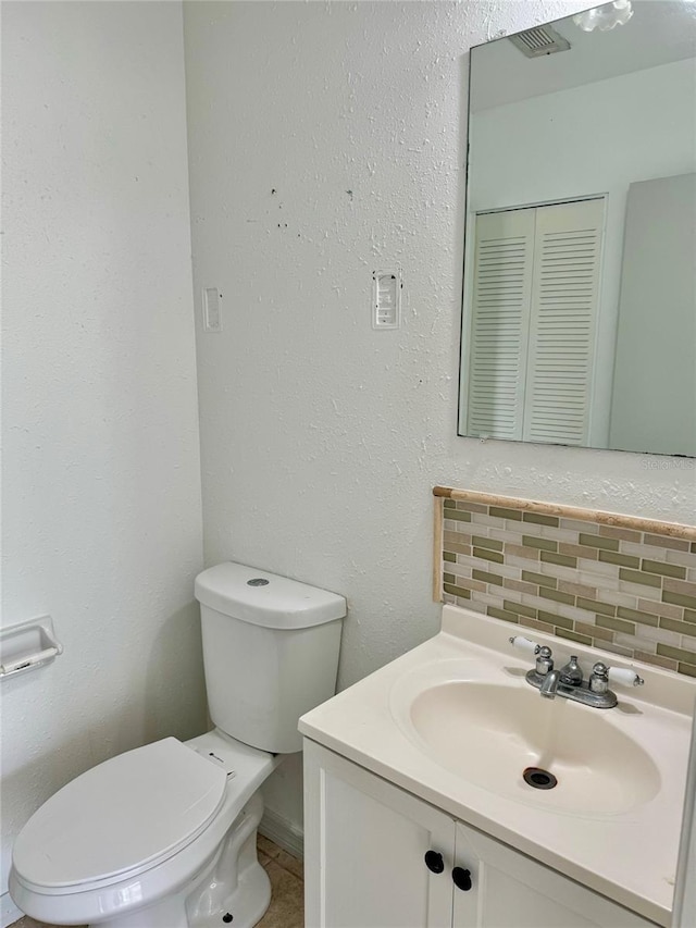 half bath featuring backsplash, toilet, and vanity