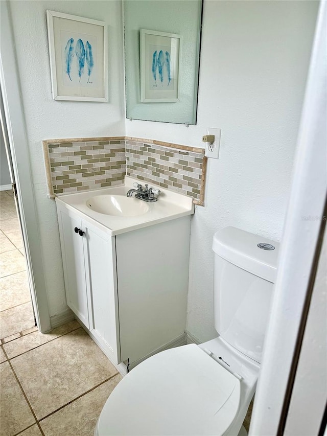 half bathroom featuring tasteful backsplash, tile patterned flooring, vanity, and toilet