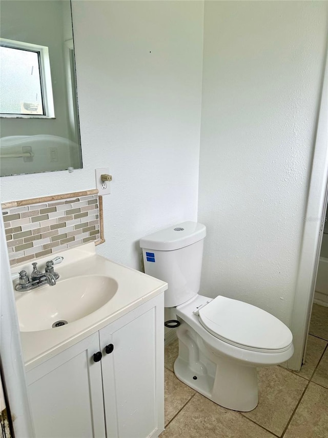 half bathroom featuring toilet, vanity, decorative backsplash, and tile patterned floors