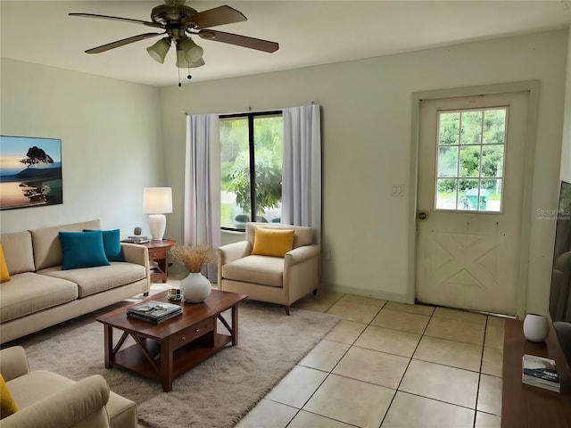 living room with light tile patterned floors, ceiling fan, and baseboards