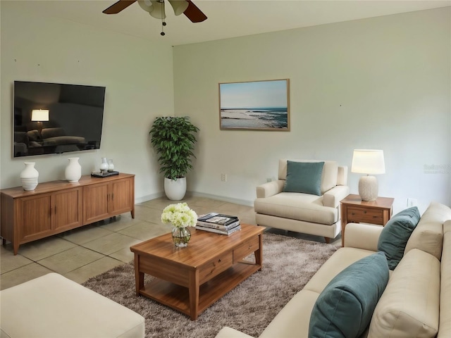 living area featuring light tile patterned floors, ceiling fan, and baseboards