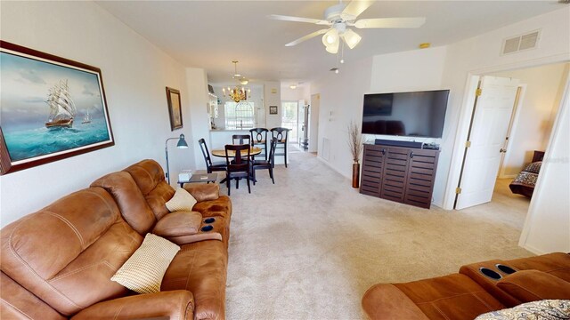 carpeted living room featuring ceiling fan with notable chandelier