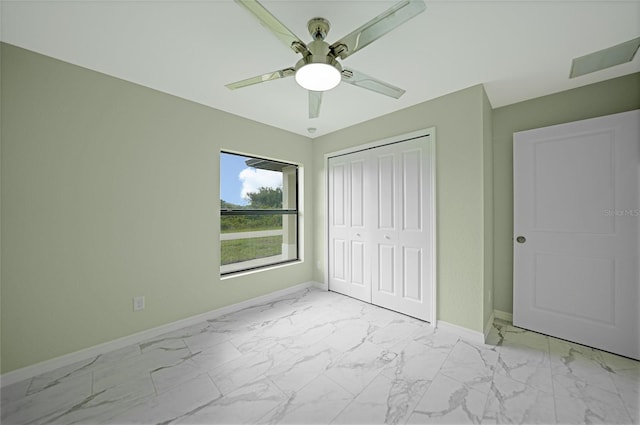 unfurnished bedroom featuring a closet, marble finish floor, ceiling fan, and baseboards