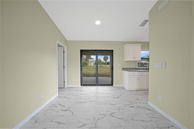 interior space featuring lofted ceiling, marble finish floor, visible vents, and baseboards