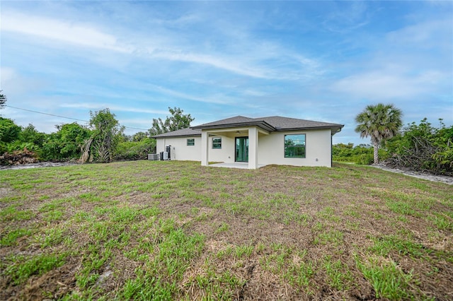 rear view of property with a patio area, a yard, and central AC