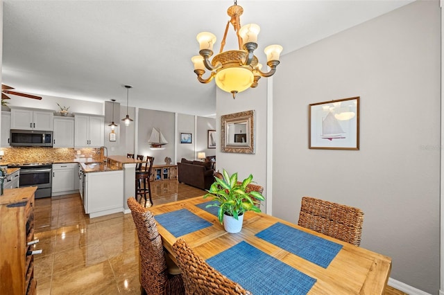 dining room with sink and ceiling fan with notable chandelier