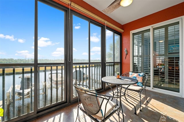 sunroom / solarium featuring ceiling fan and a water view