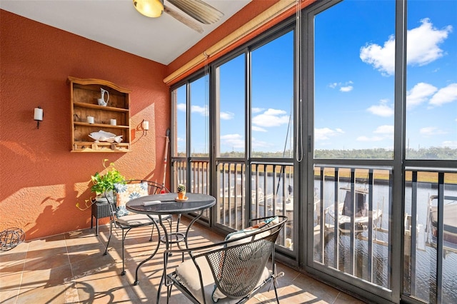 sunroom / solarium featuring a water view and ceiling fan