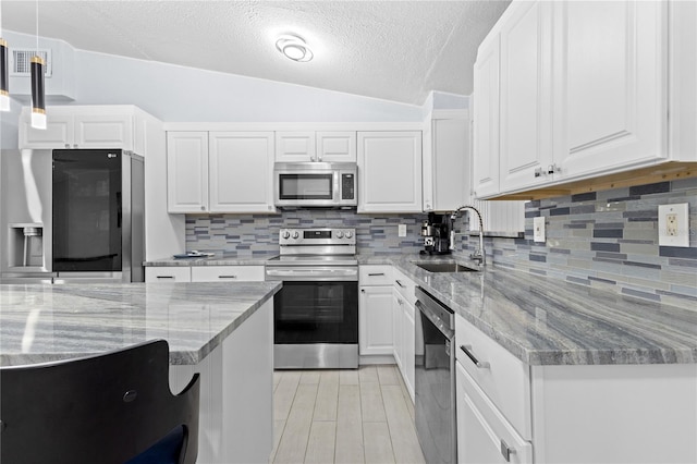 kitchen featuring stainless steel appliances, backsplash, hanging light fixtures, white cabinetry, and sink