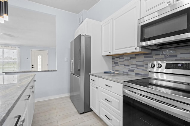 kitchen with backsplash, appliances with stainless steel finishes, decorative light fixtures, and white cabinets