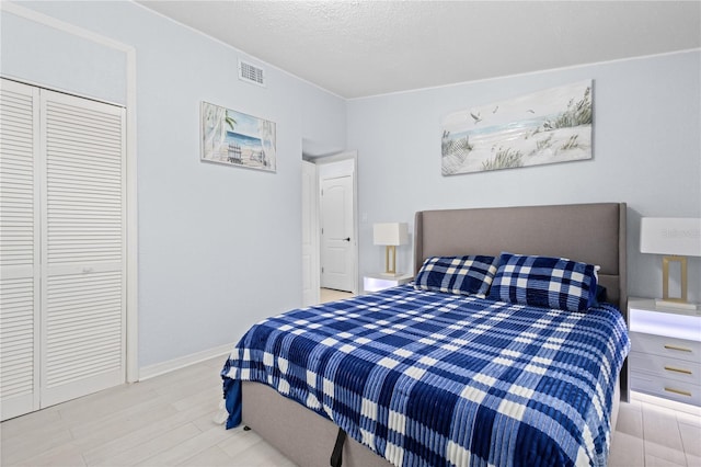 bedroom with light hardwood / wood-style floors, a closet, and a textured ceiling