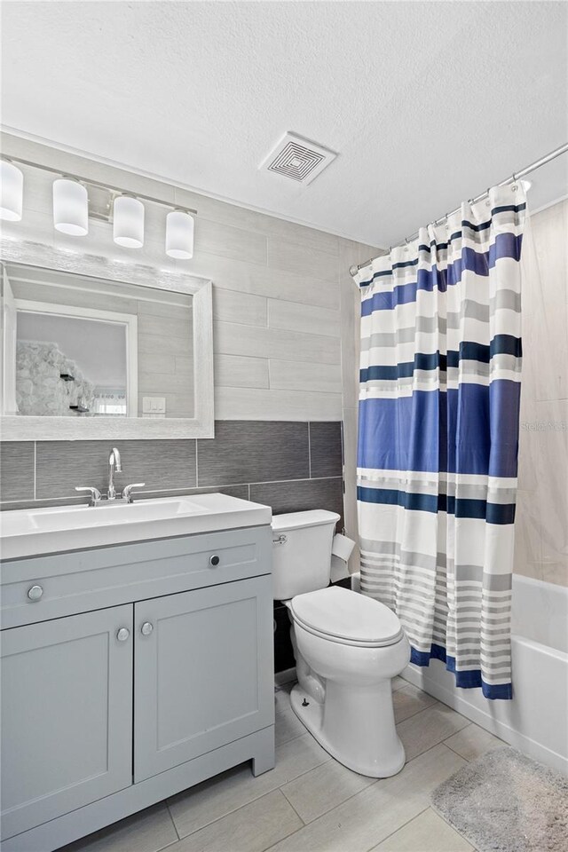 full bathroom featuring tile flooring, tile walls, shower / bathtub combination with curtain, toilet, and vanity