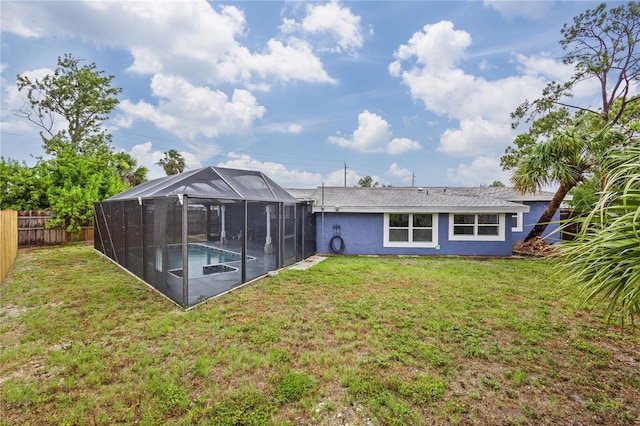 rear view of property with glass enclosure, a yard, and a fenced in pool