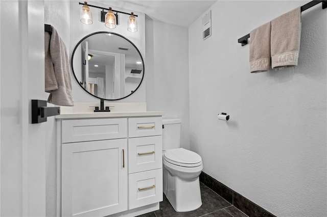 bathroom with toilet, vanity, and tile patterned flooring