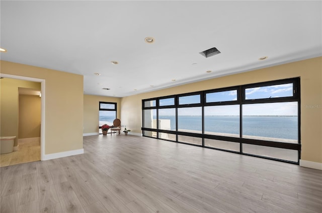 empty room with light hardwood / wood-style flooring and a water view