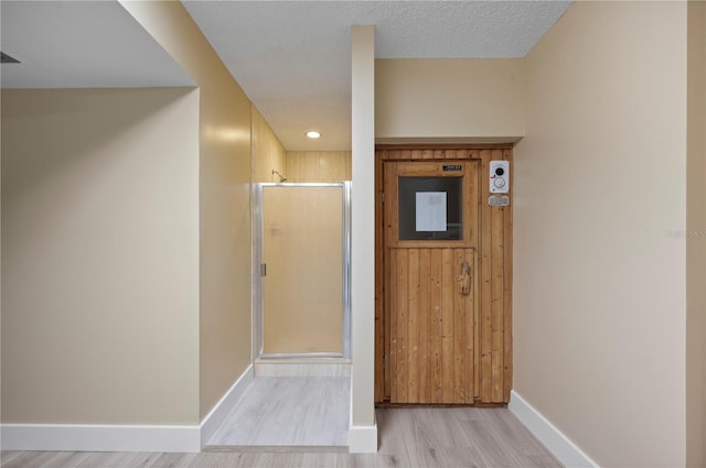 hall featuring a textured ceiling and light hardwood / wood-style flooring