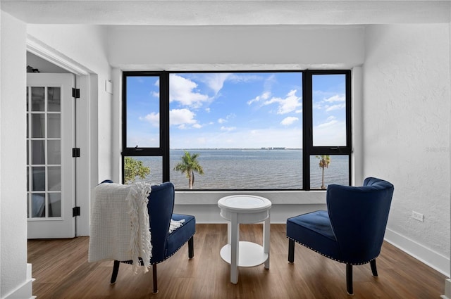 sitting room with hardwood / wood-style floors and a water view