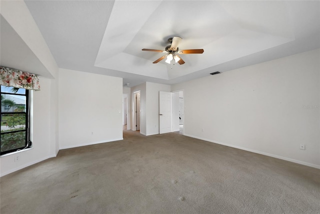 interior space with carpet, ceiling fan, and a raised ceiling