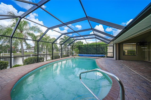 view of swimming pool with glass enclosure, a patio area, and a water view