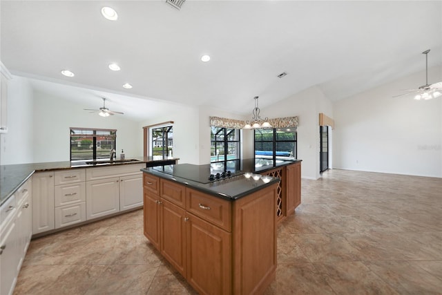 kitchen featuring black electric cooktop, sink, hanging light fixtures, and vaulted ceiling