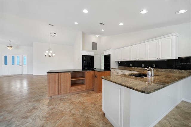 kitchen featuring kitchen peninsula, dark stone counters, sink, white cabinetry, and hanging light fixtures