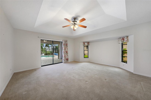 carpeted spare room featuring ceiling fan and a raised ceiling