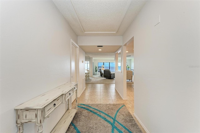 corridor with light tile patterned floors and a textured ceiling