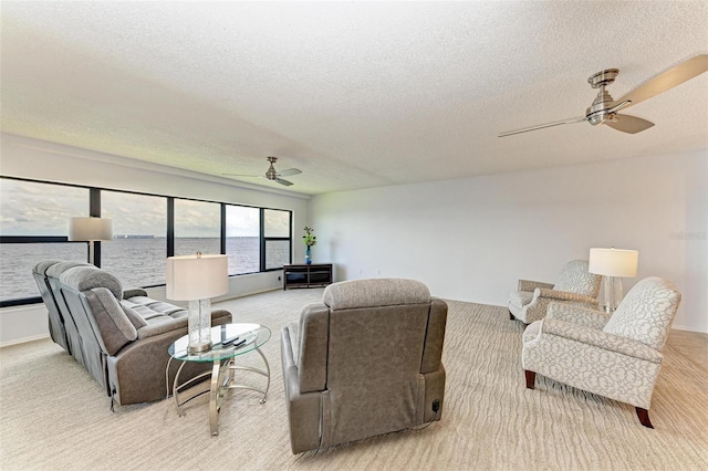 carpeted living room with a textured ceiling, a water view, and ceiling fan