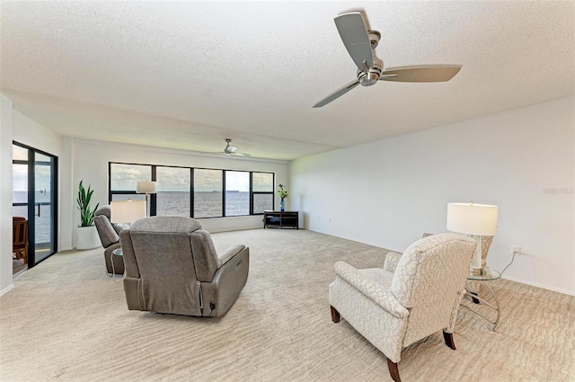 living room featuring ceiling fan, light colored carpet, and a textured ceiling