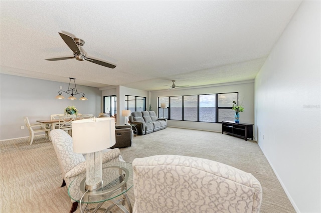 living room with ceiling fan, light colored carpet, and a textured ceiling