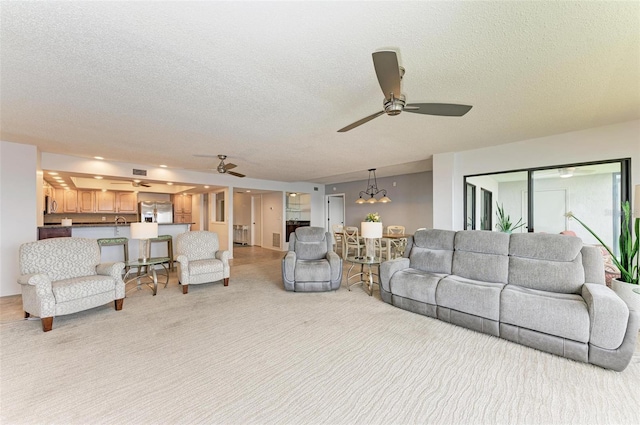 living room with ceiling fan with notable chandelier and a textured ceiling