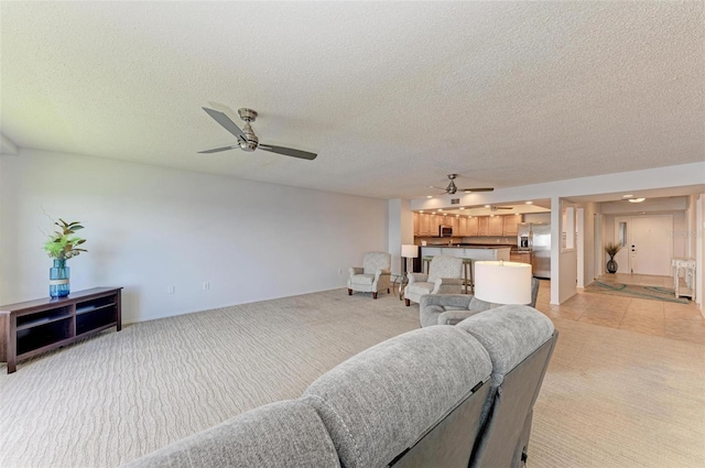 carpeted living room featuring ceiling fan and a textured ceiling