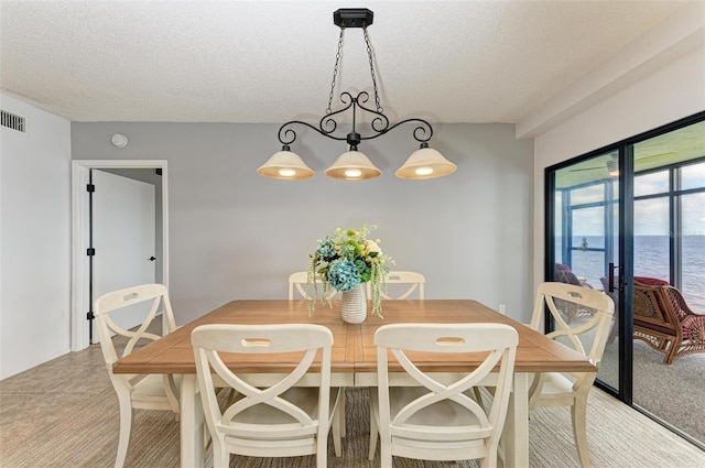 dining space featuring a water view and a textured ceiling