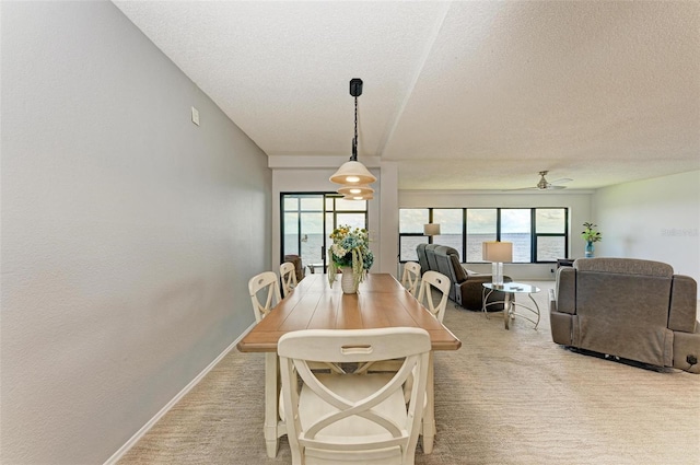 dining area featuring ceiling fan, light colored carpet, and a textured ceiling