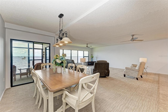 dining area with a textured ceiling, a water view, and ceiling fan