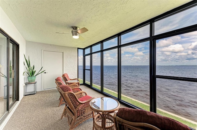 sunroom / solarium with ceiling fan and a water view