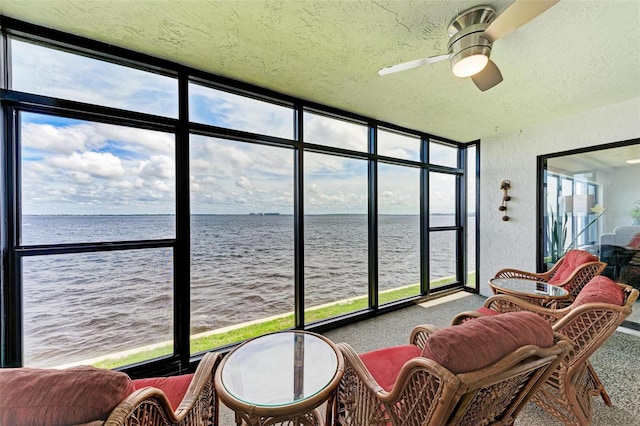 sunroom / solarium with ceiling fan, a water view, and plenty of natural light