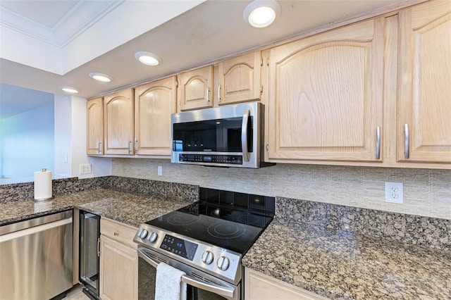 kitchen with crown molding, dark stone countertops, stainless steel appliances, and light brown cabinetry