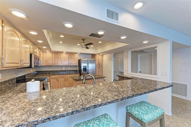 kitchen with a raised ceiling, kitchen peninsula, and appliances with stainless steel finishes