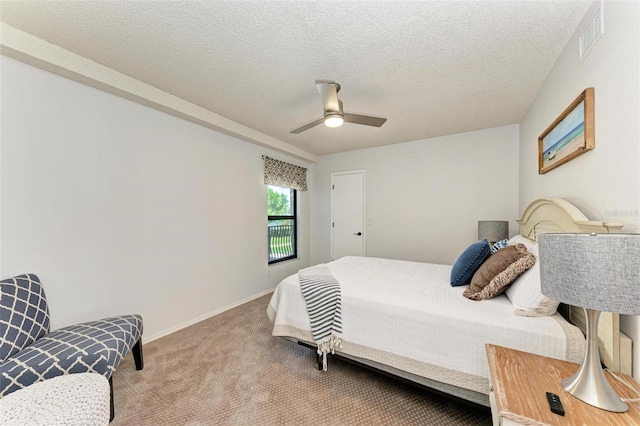 carpeted bedroom featuring ceiling fan and a textured ceiling