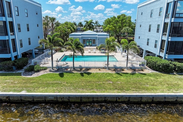 view of swimming pool featuring a lawn, a water view, and a patio